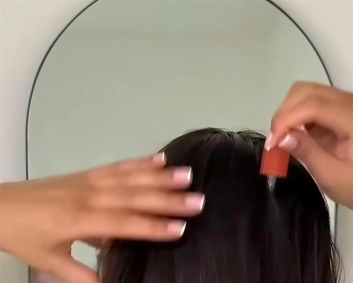 Fingers opening a clean parting in dry hair so the scalp shows